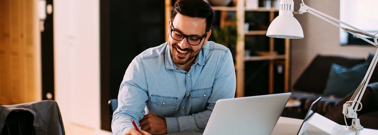 Jonge zakenman die thuis werkt met laptop en papieren op bureau