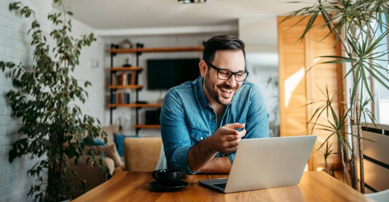 Man achter laptop in thuisomgeving